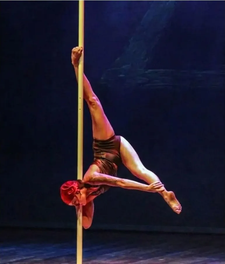Figura invertida en la barra durante una actuación de pole dance